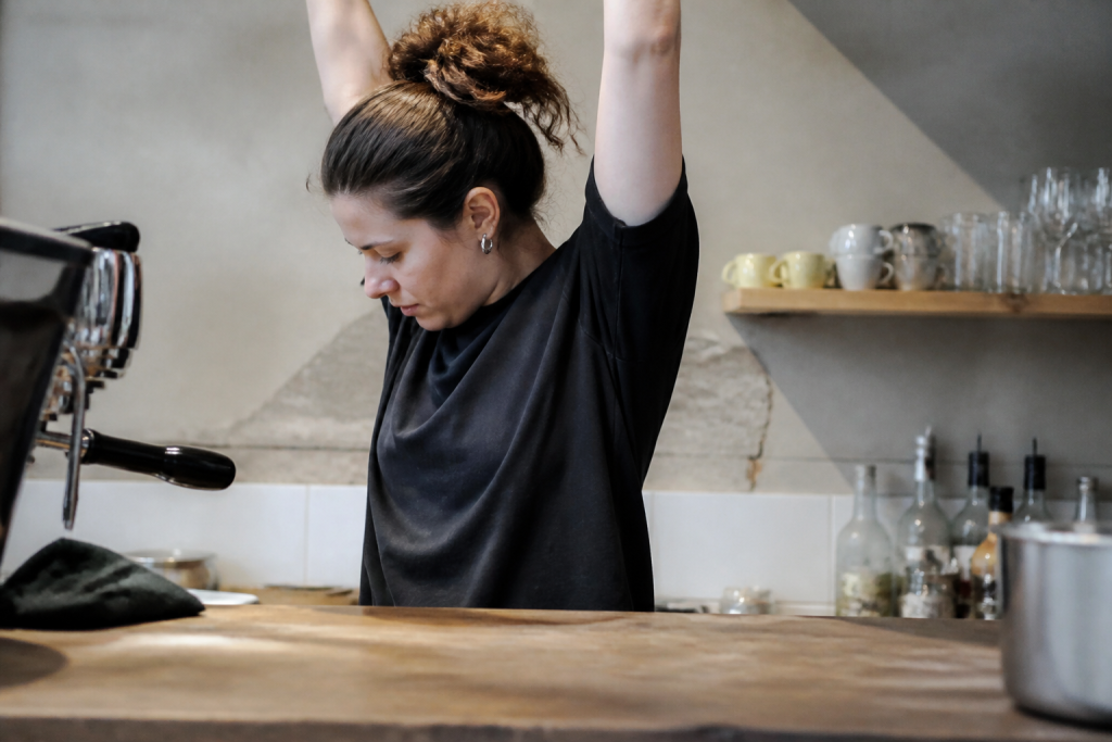 Femme bras leves epaules contractees travaillant a comptoir