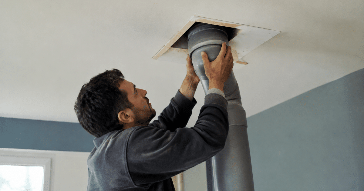 Technicien installe conduit VMC vertical dans plafond sans demolition
