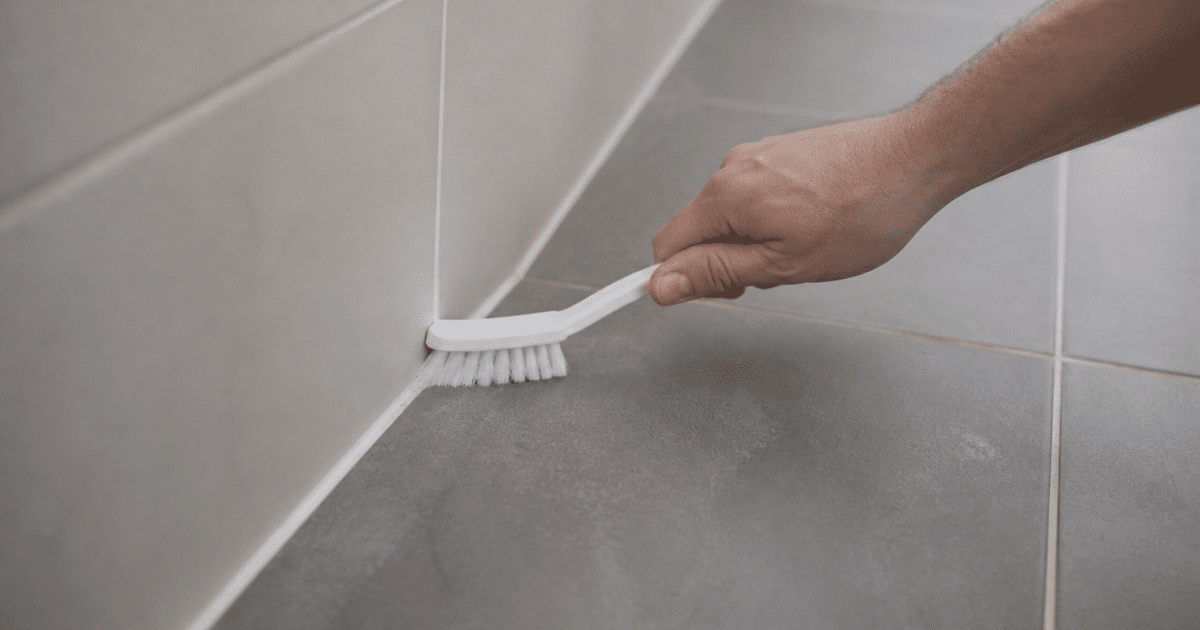 Mains tenant brosse appliquee sur joints carrelage gris