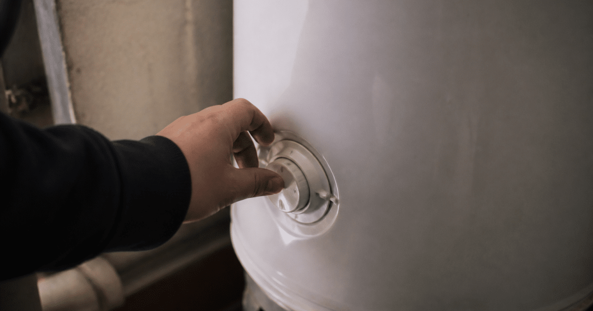 Main tournant le bouton de thermostat sur reservoir metallique blanc