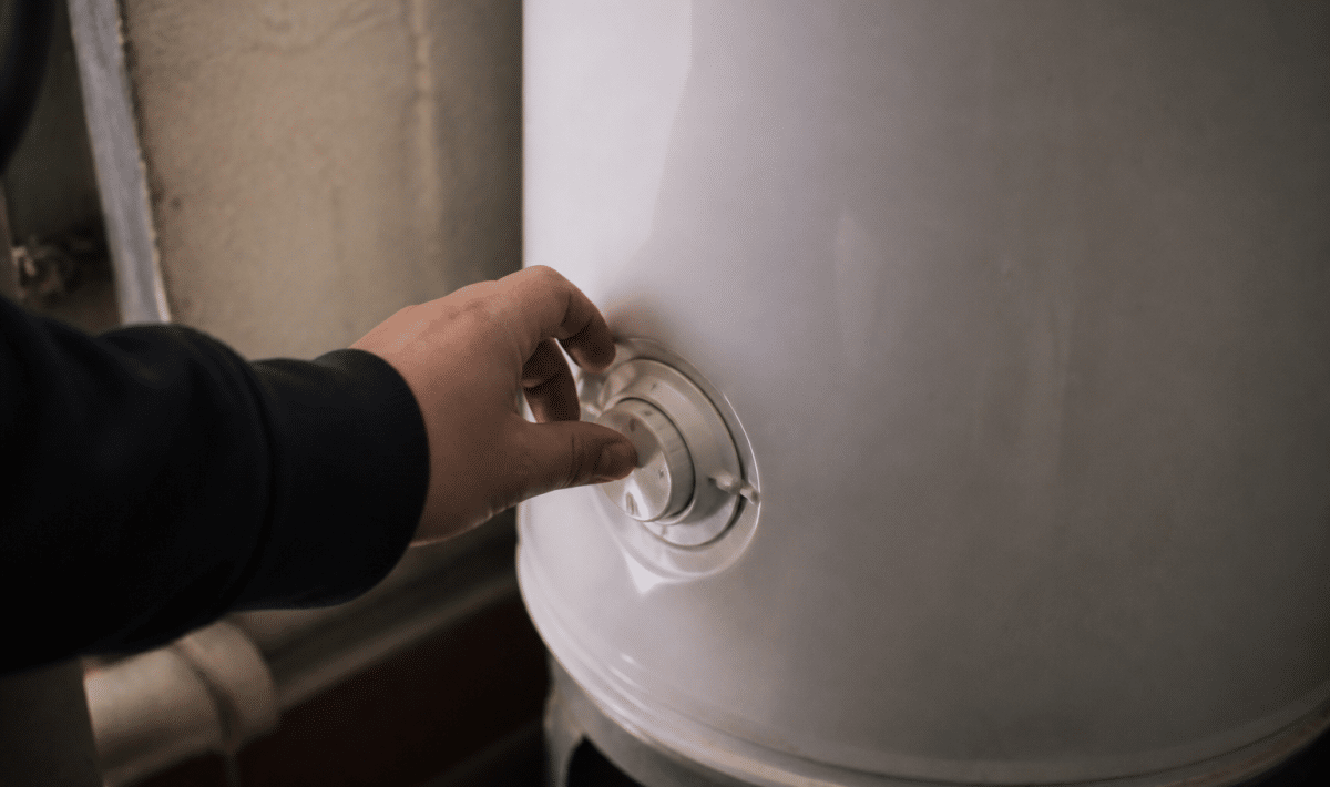 Main tournant le bouton de thermostat sur reservoir metallique blanc