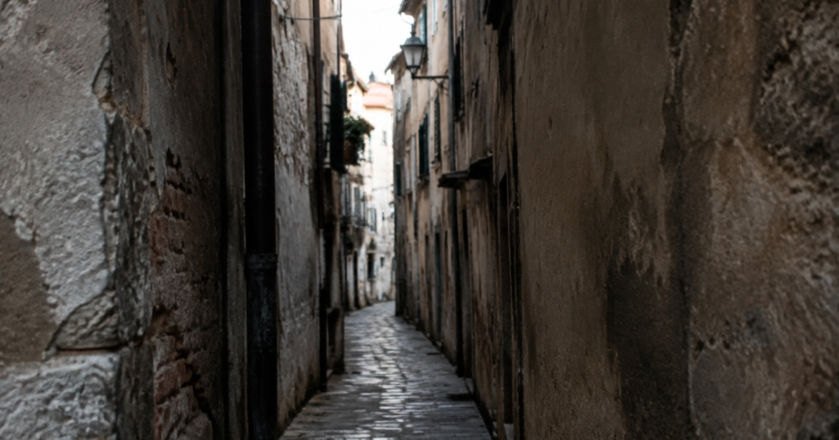 Batiments deteriores encadrant une rue etroite et sombre